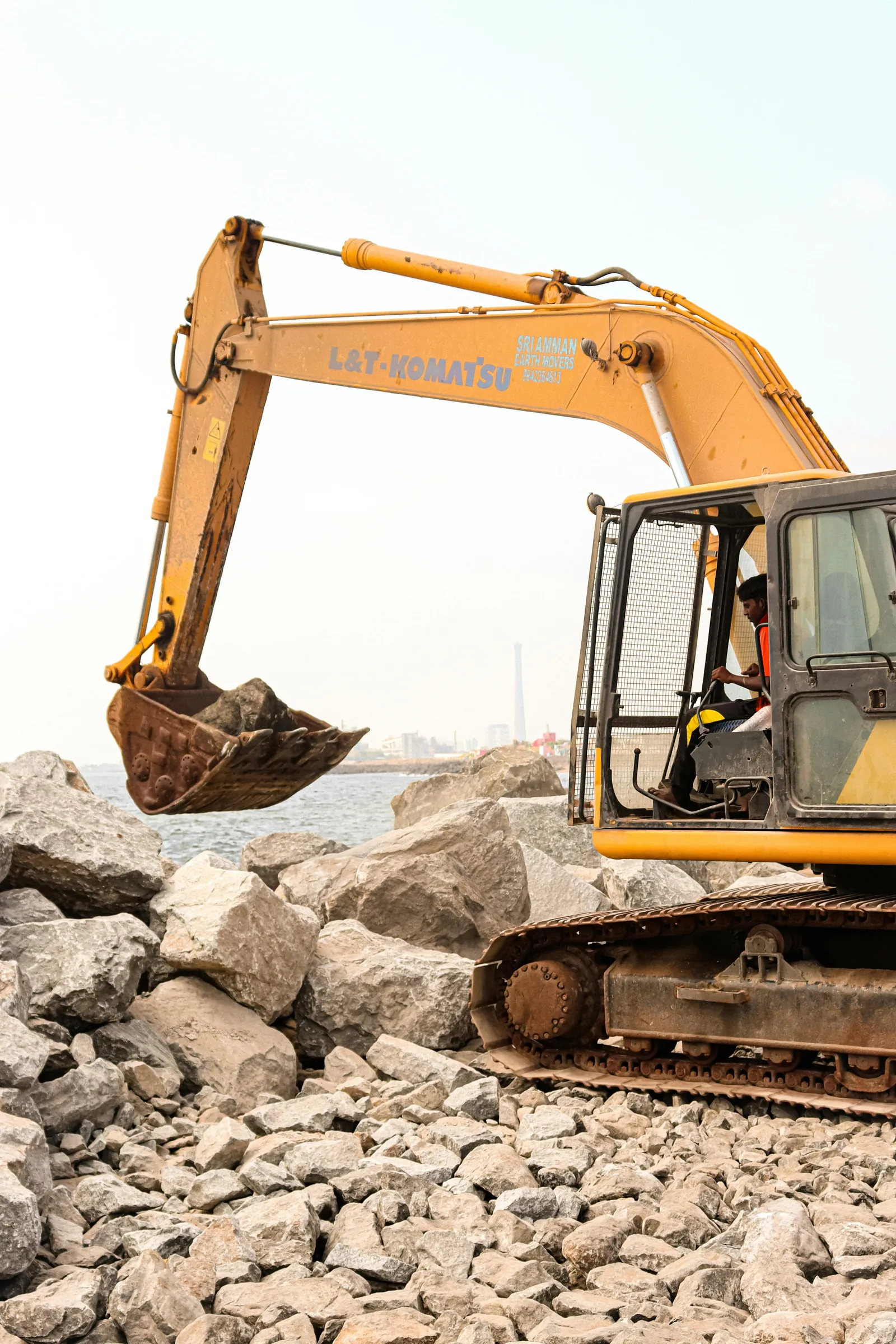 Construction excavator operating over a rocky work area.